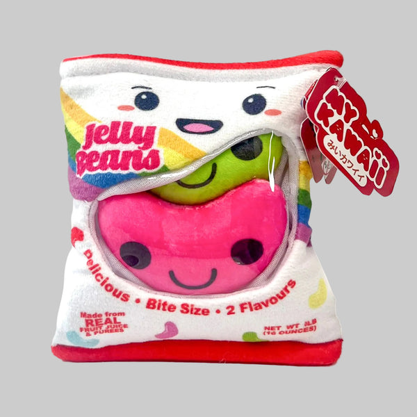 A plush jelly bean toy shaped like a candy bag, featuring a white bag design with red trim, a pink jelly bean face on the front, a green jelly bean peeking out behind it, and a red hanging tag with Japanese text.
